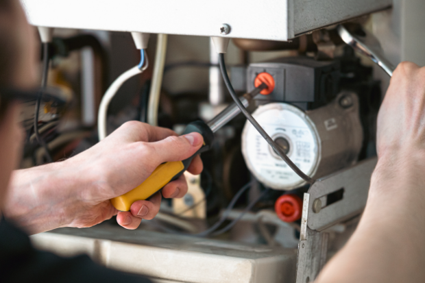 A technician is repairing a water-heating boiler, close-up.