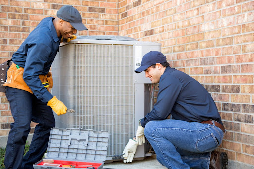 Multi-ethnic team of blue collar air conditioner repairmen at work. They prepare to begin work by gathering appropriate tools from their tool box for ac maintenance in Tampa, FL.